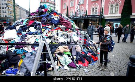 Praga, Repubblica Ceca. 12 novembre 2024. Il 12 novembre 2024 un ragazzo si trova accanto a una pila di vestiti creati per sensibilizzare sulla questione dei rifiuti tessili a Praga, Repubblica Ceca. Crediti: Dana Kesnerova/Xinhua/Alamy Live News Foto Stock