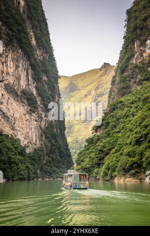 Una barca sul fiume NHO Que nella provincia di ha Giang, Vietnam. Il fiume si snoda attraverso le torreggianti scogliere calcaree del Dong Van Karst Plateau Geopark Foto Stock