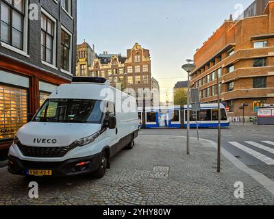 Amsterdam Paesi Bassi 24 novembre 2024, un furgone bianco parcheggiato accanto a edifici storici mentre passa un tram, dal 2025 Amsterdam sarà in grado di ospitare Foto Stock