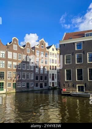 Amsterdam Paesi Bassi 24 novembre 2024, Una pittoresca vista delle iconiche case sui canali di Amsterdam, che mostrano la loro architettura unica su un blu luminoso Foto Stock