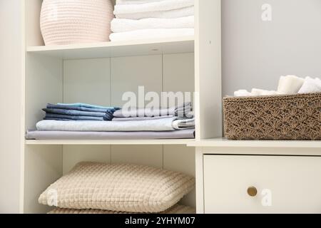 Organizzazione tessile per la casa. Asciugamani piegati, lenzuola e cuscini sugli scaffali interni, primo piano Foto Stock