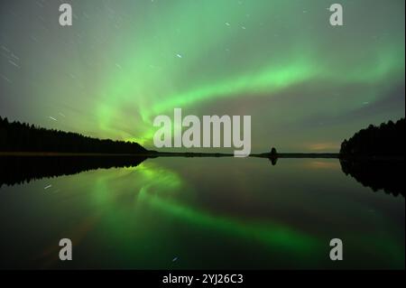 L'immagine cattura l'aurora boreale, o aurora boreale, ballando attraverso il cielo notturno, con un verde brillante e sottili accenni di altri colori riflessi Foto Stock