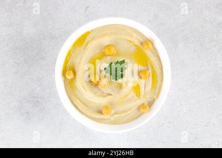 Hummus classico con prezzemolo e olio d'oliva in un piatto su sfondo grigio, vista dall'alto. Cucina araba e turca. Foto Stock