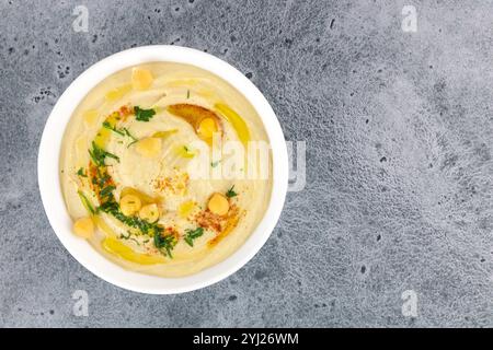 Hummus classico con prezzemolo e olio d'oliva in un piatto su sfondo grigio, vista dall'alto. Copia spazio. Cucina araba e turca Foto Stock