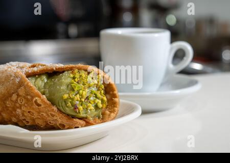 Vista dettagliata dei cannoli ripieni di panna di pistacchio con noci schiacciate tradizionale pasticceria siciliana servita con caffè espresso italiano Foto Stock