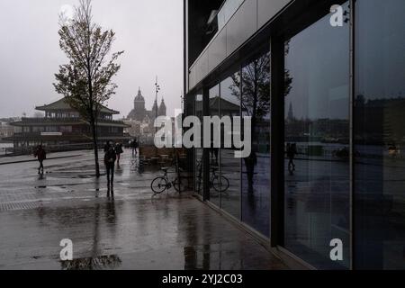 Scena piovosa dell'uscita dalla biblioteca centrale dell'OBA con la Basilica di San Nicola nell'Oosterdokade nella città di Amsterdan, in Olanda Foto Stock