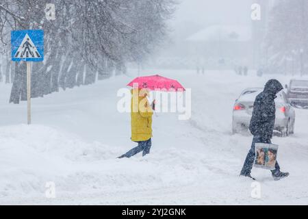 Ucraina, città di Romny, 01.08.2016: Una strada nevosa durante una forte nevicata. Passeggiata trasversale. C'è molta neve sul marciapiede, sulle auto e sui rami degli alberi. PEO Foto Stock