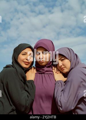 Tre donne in coloratissimi hijab in piedi vicini sotto un cielo blu con nuvole, Marocco Foto Stock