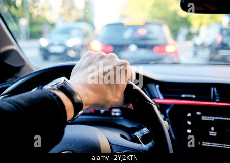 La mano del conducente sul volante di un'auto durante un ingorgo Foto Stock