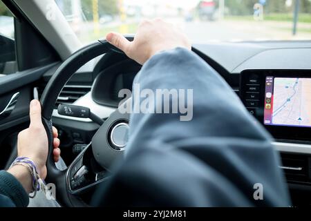 Mano del conducente sul volante con una mappa di navigazione visualizzata sul touch screen dell'auto, Bruxelles, Belgio Foto Stock