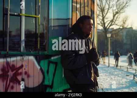 Young Man in piedi accanto a una capanna ricoperta di graffiti in un parco pubblico in una giornata di neve, Berlino, Germania Foto Stock