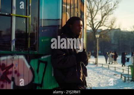 Young Man in piedi accanto a una capanna ricoperta di graffiti in un parco pubblico in una giornata di neve, Berlino, Germania Foto Stock