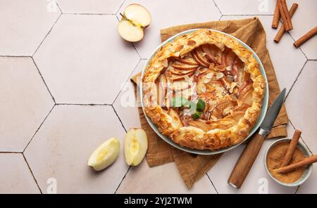 galette di mele appena sfornata decorata con fiocchi di mandorle, cannella e foglie di menta, servita su un piatto Foto Stock