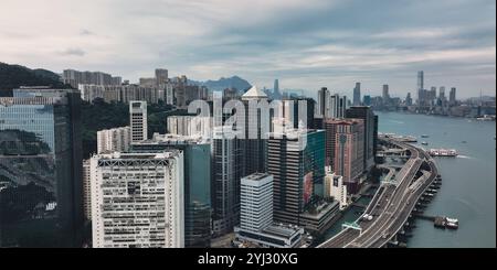 Victoria Bay rivela uno splendido paesaggio urbano di Hong Kong con edifici torreggianti e il tranquillo porto sotto nuvole grigie. Foto Stock