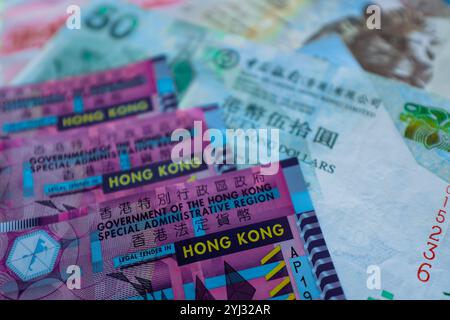 Vista ravvicinata di varie banconote e monete di Hong Kong con disegni intricati e colori vivaci. Foto Stock