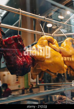 In un affollato ristorante di Hong Kong è esposto un colorato spettacolo di carni arrosto che attira i clienti all'ora di pranzo con aromi seducenti. Foto Stock