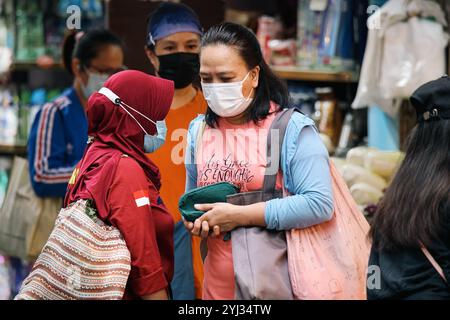 Due donne si impegnano in conversazione mentre fanno shopping in un vivace mercato di Hong Kong, mostrando l'atmosfera vivace della zona. Foto Stock