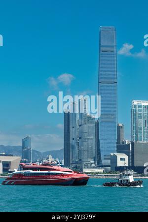 Un traghetto naviga le acque da Macao a Hong Kong, con edifici alti e un cielo azzurro trasparente visibile sullo sfondo. Foto Stock