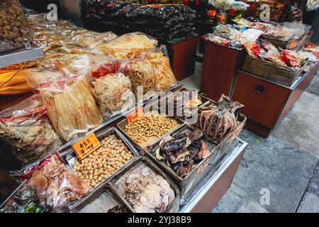 Un vivace mercato di Hong Kong presenta vari piatti di pesce secco e ingredienti locali esposti in confezioni colorate. Foto Stock