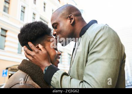 Coppia romantica che condivide un momento tenero in un giorno di sole in City Street Foto Stock