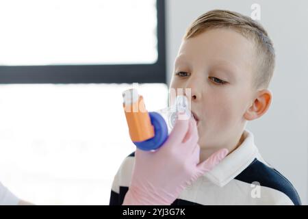 Ragazzo con asma allergica, inalando il farmaco attraverso Spacer mentre è seduto nell'ufficio medico. Foto Stock