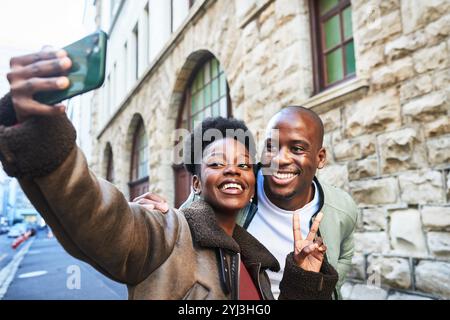 Coppia felice che porta un selfie su una strada cittadina, catturando momenti di gioia insieme in un ambiente urbano Foto Stock