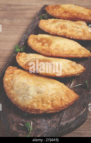 Cheburek fritte, fritte in profondità, mini, su un tagliere, tavolo di legno, primo piano, nessuna gente Foto Stock