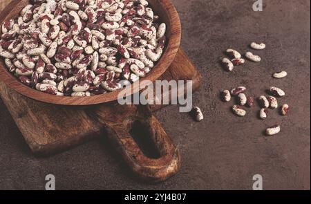 Fagioli variegati, rossi con macchie bianche, crudi in una ciotola di legno, vista dall'alto, nessuna gente Foto Stock