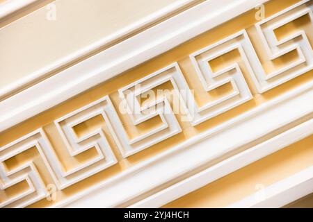 Decorazione delle pareti con motivo bianco Meander su sfondo giallo, modello di architettura antica classica, texture fotografica di sfondo Foto Stock