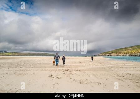 Persone che camminano con i cani durante la bassa marea sulla spiaggia di Crantock a Newquay, in Cornovaglia, nel Regno Unito. Foto Stock