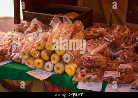 Un bancone del mercato che espone una varietà di ciambelle appena sfornate in una confezione in plastica trasparente, con diversi tipi e sapori, perfetto per un dolce tr Foto Stock