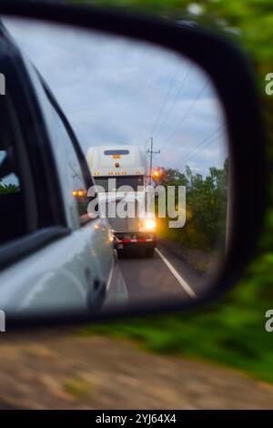 Un grande camion visto dietro un'auto attraverso lo specchio retrovisore, Costa Rica Foto Stock