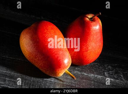 pera rossa su sfondo in legno nero Foto Stock