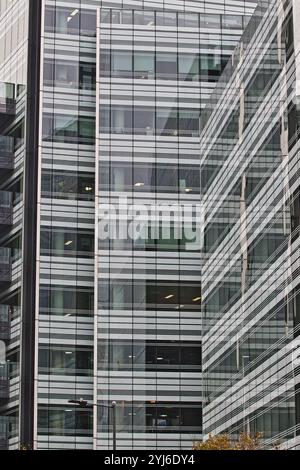 Una vista ravvicinata di un moderno edificio di uffici caratterizzato da finestre a griglia. L'edificio e' composto da vetro e metallo, con un elegante e co Foto Stock