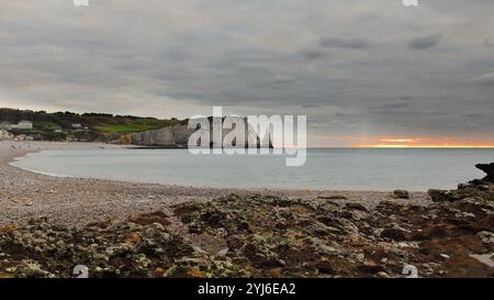 017 Falaise d'Aval Cliff, Porte d'Aval Archway, Aiguille Creuse Needle, cielo colorato al tramonto, visto verso ovest dall'altra parte della spiaggia. Etretat-Francia Foto Stock