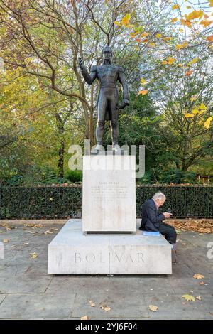 Un uomo siede sul basamento della Scultura di Simon Bolivar di Hugo Daini in Belgrave Square Londra SW1. Foto Stock