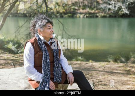 Una donna cubana gode di un momento di pace seduto sul fiume tranquillo di Fragas do Eume, Galizia, Spagna Foto Stock