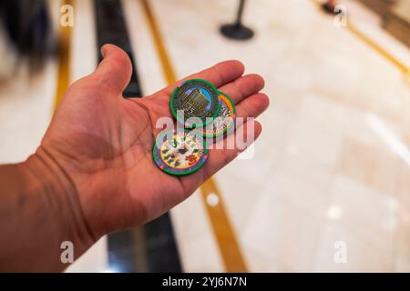 Mano che regge tre chip del casinò dal Palazzo di Las Vegas, ambiente interno con sfondo sfocato. Las Vegas. STATI UNITI. Foto Stock