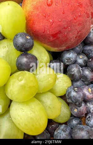 primo piano di frutta fresca, mirtilli, pesca e uva in un recipiente Foto Stock