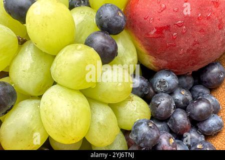 primo piano di frutta fresca, mirtilli, pesca e uva in un recipiente Foto Stock