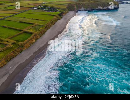 Spiaggia di Santa Barbara con sabbia vulcanica e onde turchesi dell'oceano Atlantico a Sao Miguel, Azzorre. Vista aerea della costa della città di Ribeira grande con un drone Foto Stock