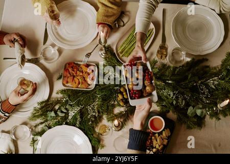 Foto dall'alto di amici irriconoscibili che bevono champagne e mangiano piatti tradizionali mentre festeggiano insieme gli X-mas Foto Stock