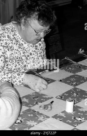 Donna caucasica di età compresa tra i 60 e i 70 anni che cucisce una trapunta al WNC Farmers Market di Asheville, North Carolina, USA. Foto Stock