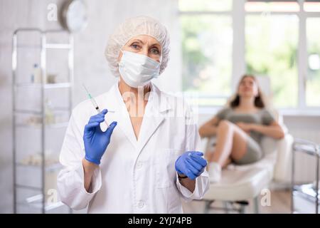 Ritratto di un medico anziano con siringa. Foto Stock