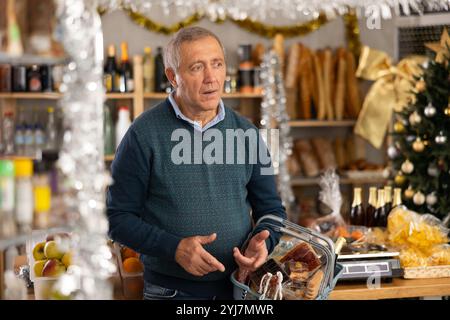 Uomo anziano con cestino di alimentari in negozio Foto Stock