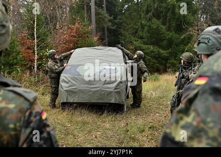 I soldati tedeschi assegnati all'Artilleriebataillon 295, 10th Armoured Division, dimostrano come posizionare pannelli mimetici su un veicolo durante il Dynamic FR Foto Stock