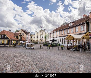 Kuldiga, Lettonia - 3 luglio 2023: Piazza del Municipio, via Baznicas, con ristoranti e strade acciottolate. Foto Stock