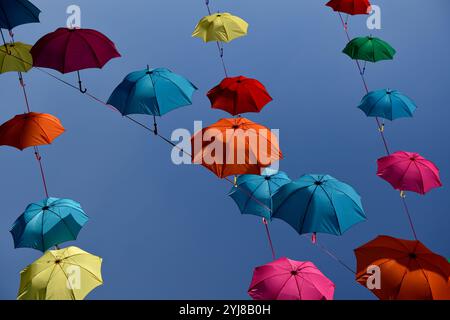 Ombrelli vivaci e colorati su uno sfondo blu chiaro del cielo. Foto Stock