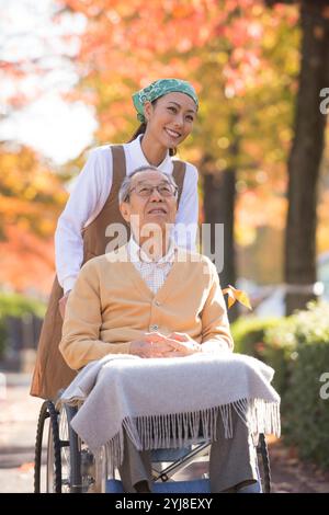 Anziano in sedia a rotelle e assistente Foto Stock