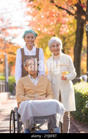 Coppia senior in sedia a rotelle e assistente Foto Stock